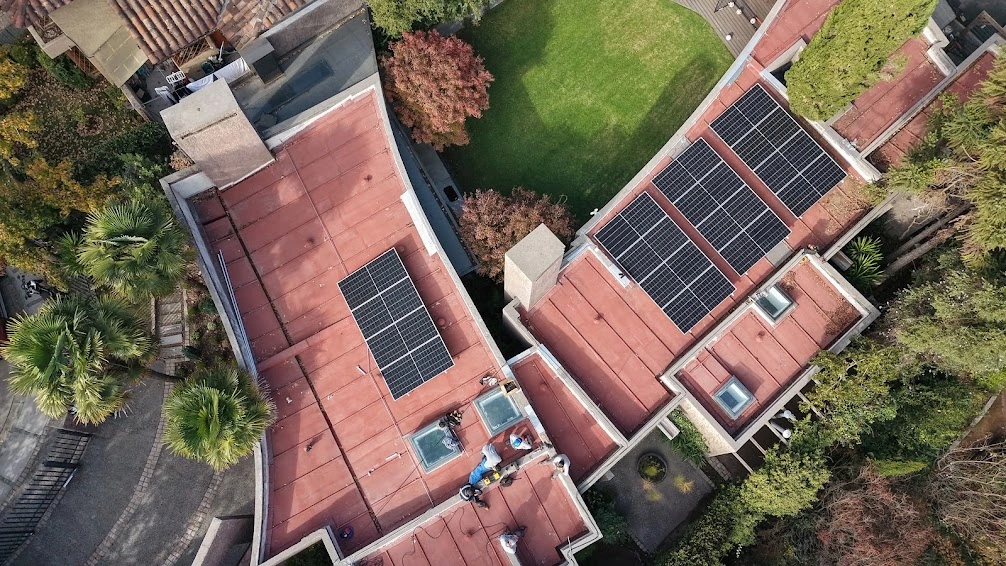Instalación fotovoltaica residencial sobre cubierta roja vista desde el aire