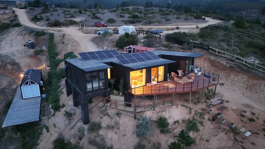 Casa con paneles fotovoltaicos y luces interiores encendidas al atardecer